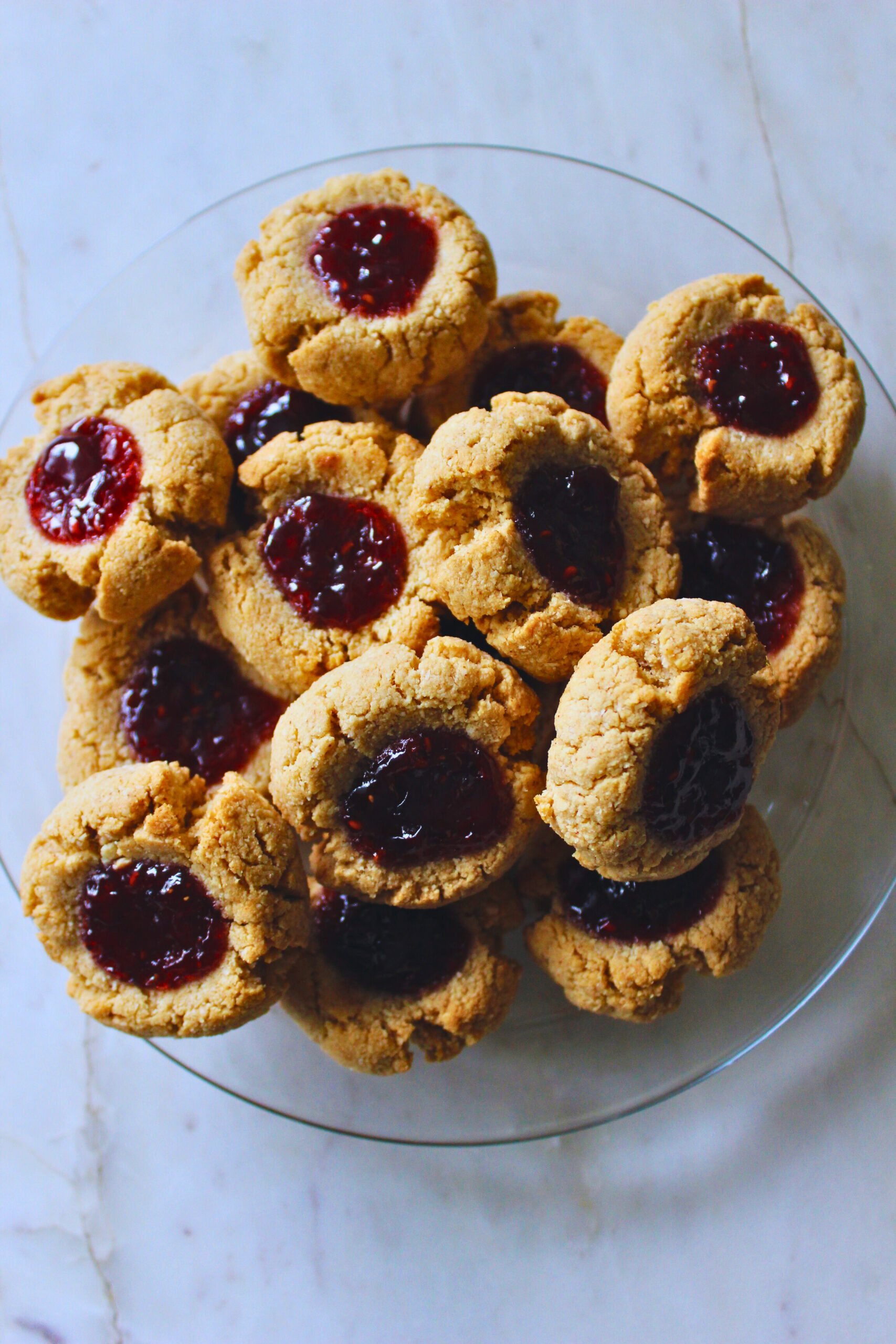 plate full of thumbprint cookies filled with fruit jam